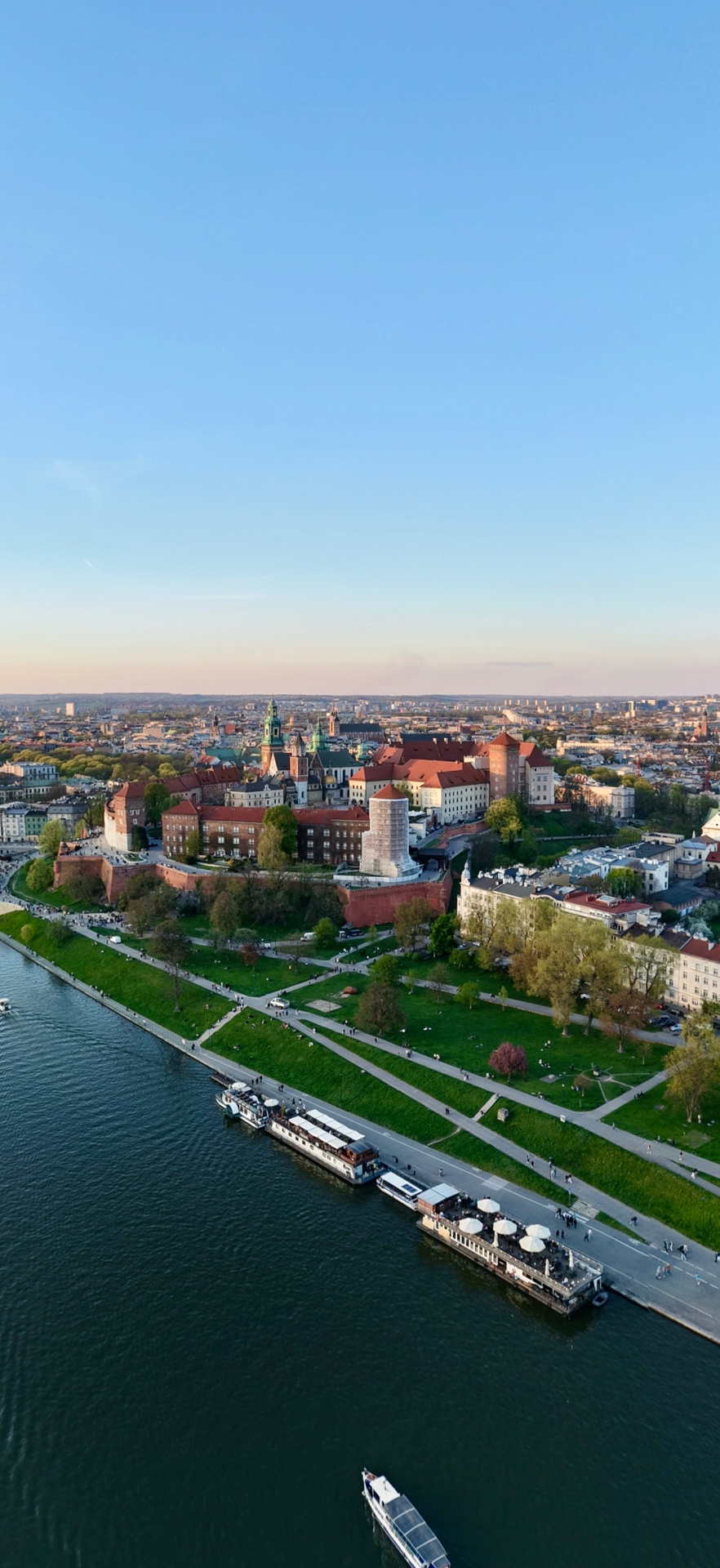 Aerial drone view of Wawel Castle and the Vistula River in Kraków, Poland at sunset