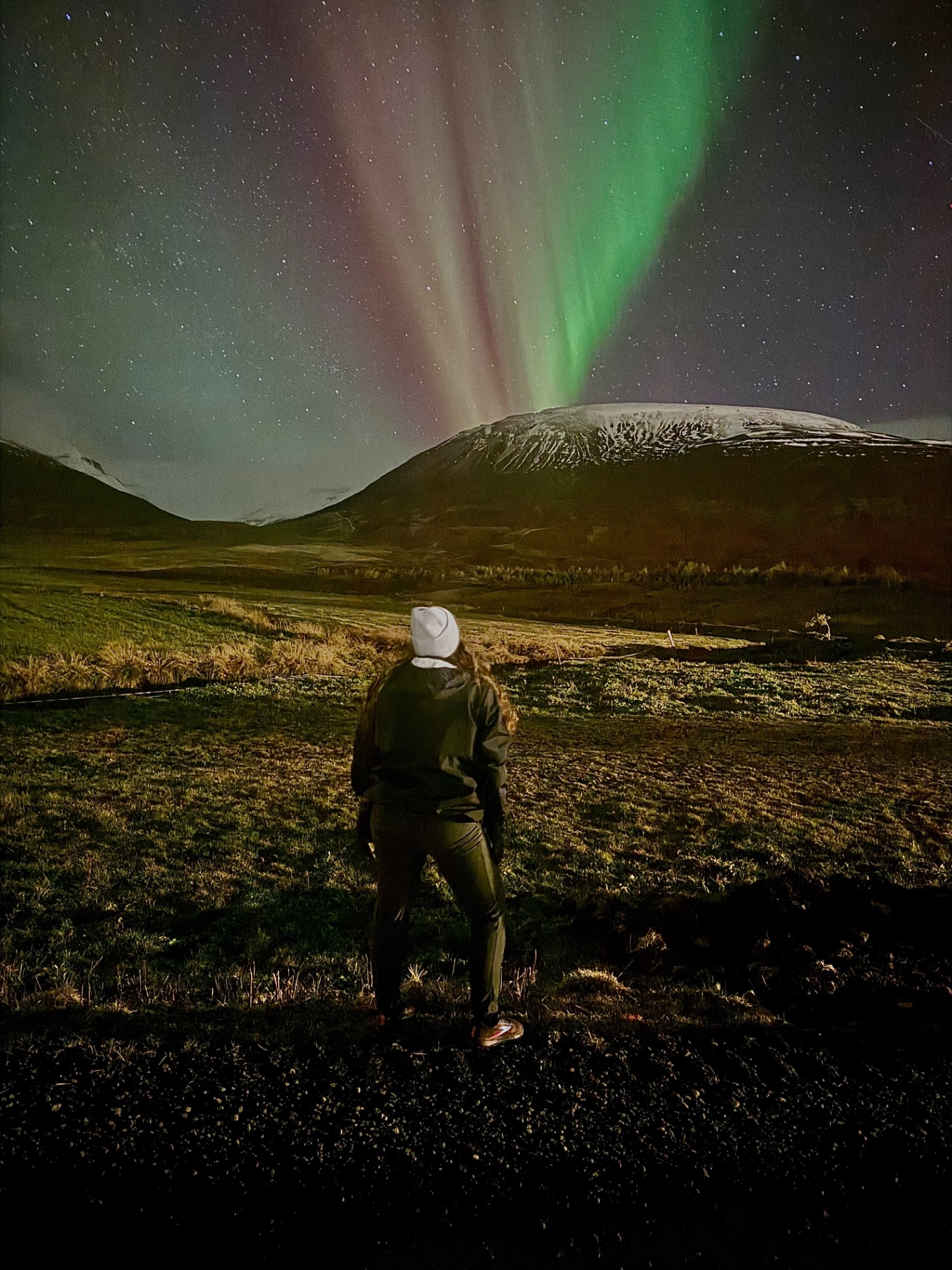 Watching the Northern Lights glow over a snowy mountain in Iceland