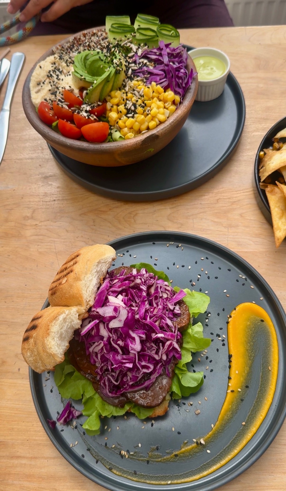 Vegan seitan sandwich topped with purple cabbage slaw beside a fresh veggie bowl in Puerto Natales, Chile
