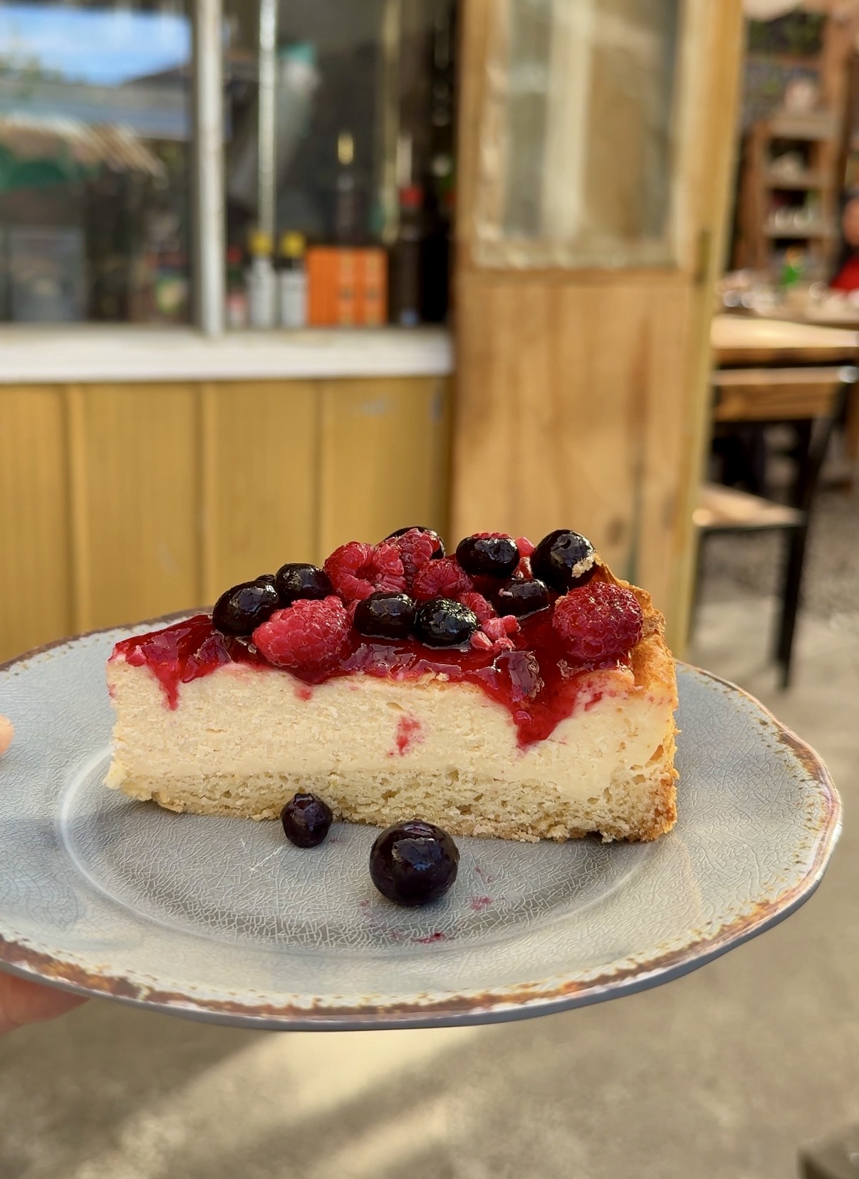 A slice of berry-topped cheesecake on a ceramic plate at Alveoli in Puerto Natales