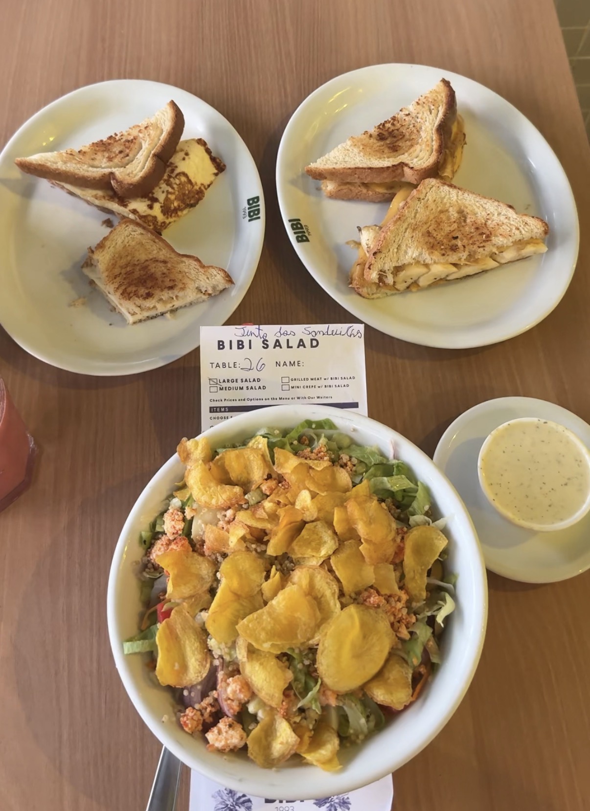 Grilled sandwiches and a large salad topped with potato chips at Bibi Salad in Rio de Janeiro