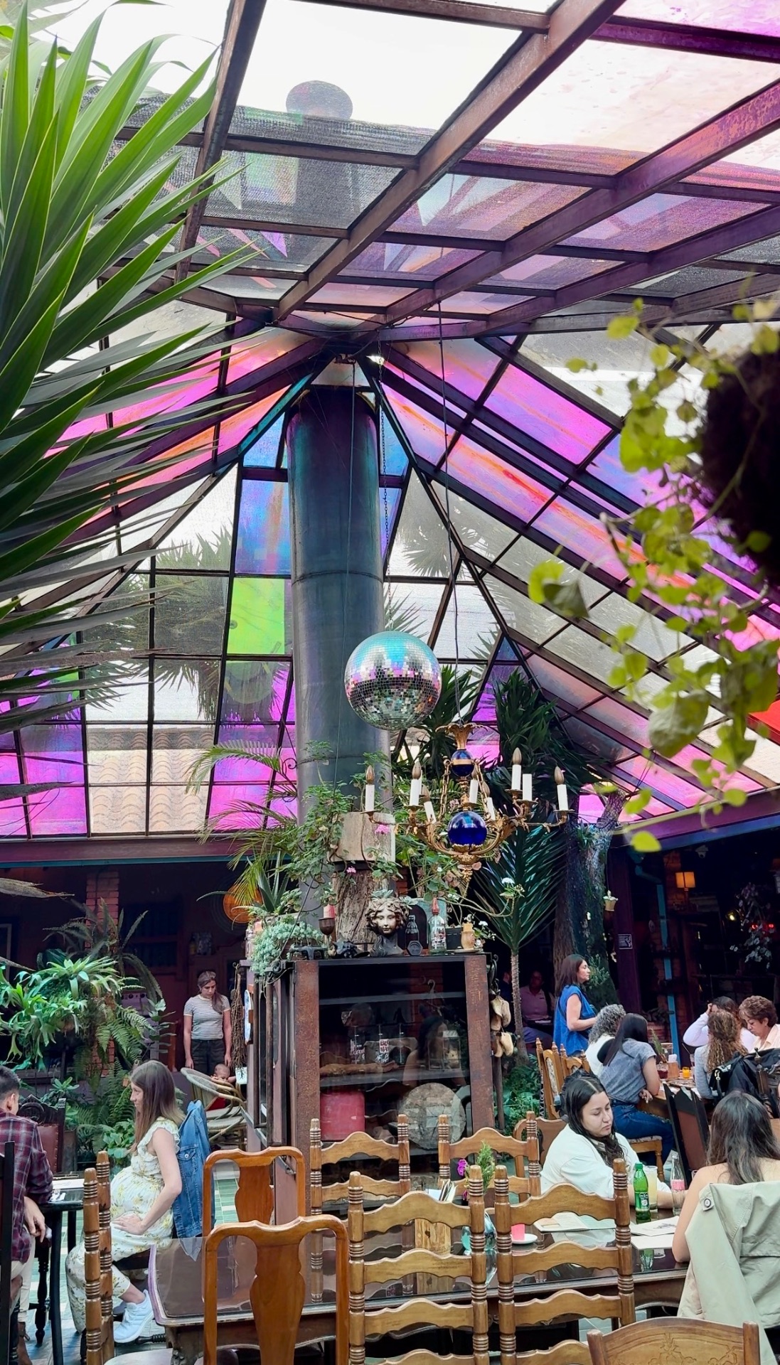 The colorful stained-glass roof and plant-filled dining room at Finca La Comadreja near Medellín
