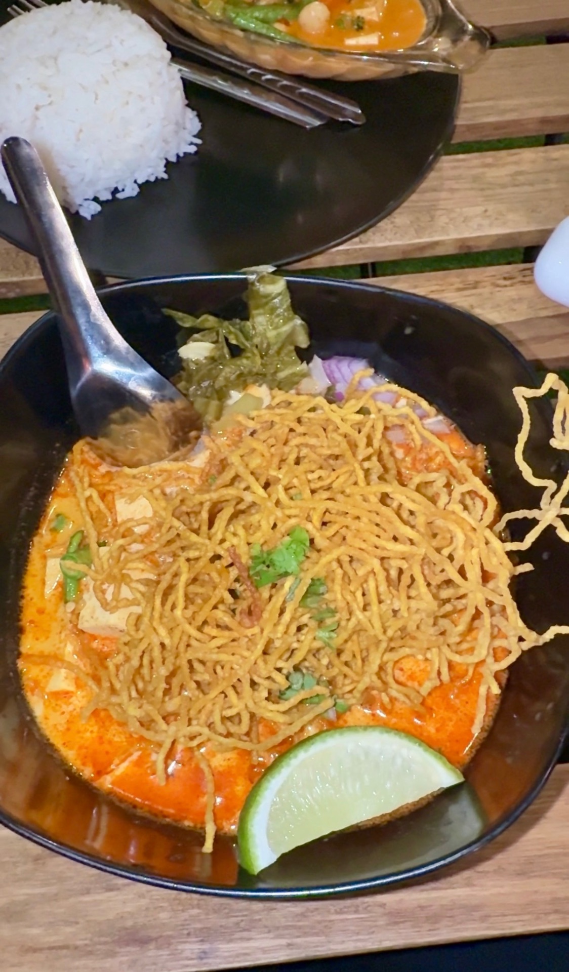 Curry noodle bowl topped with crispy noodles and a lime wedge in Chiang Rai
